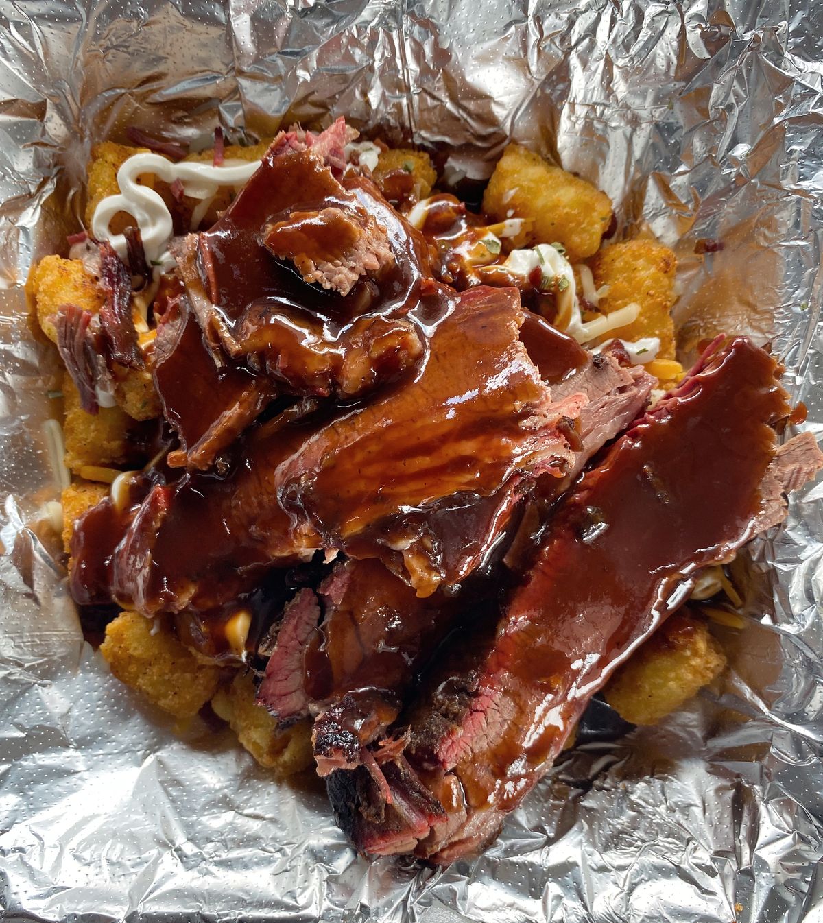 Sliced smoked brisket over loaded tater tots